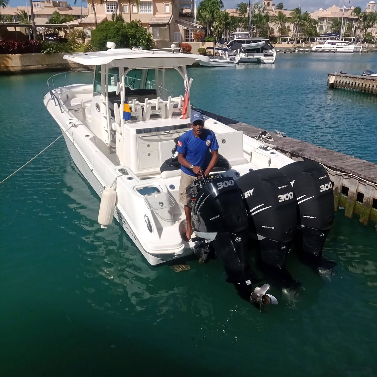 A centre-console powerboat with triple Mercury Verado 300 outboards alongside a Barbados marina, Barbados ensign flying