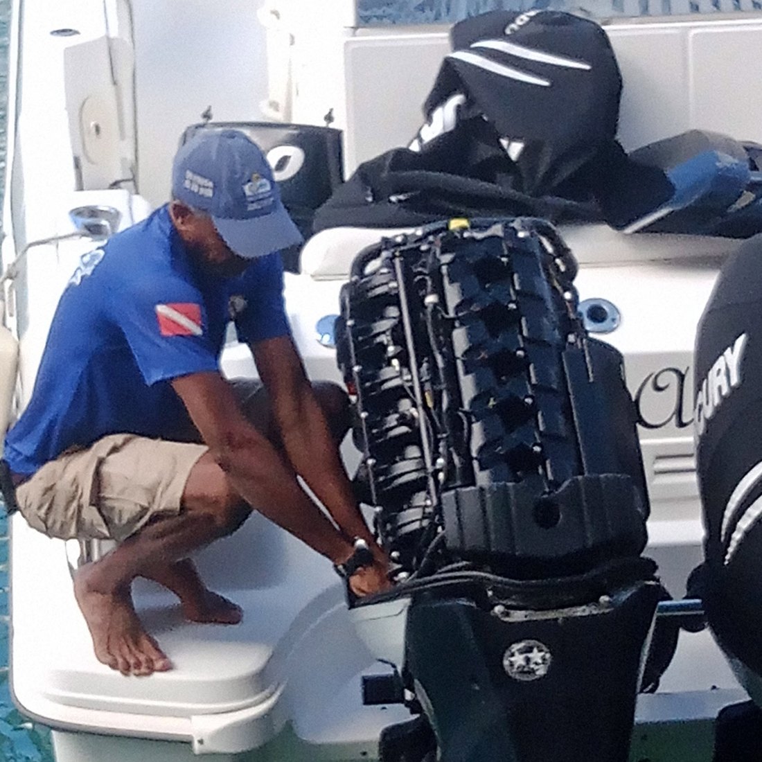 Capt. Troy Benn servicing a Mercury outboard with the cowling removed, alongside in Barbados
