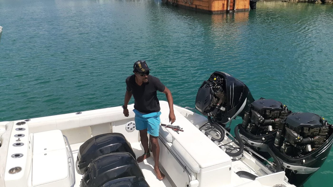 Capt. Troy Benn working on twin outboard engines with tools laid out on the transom